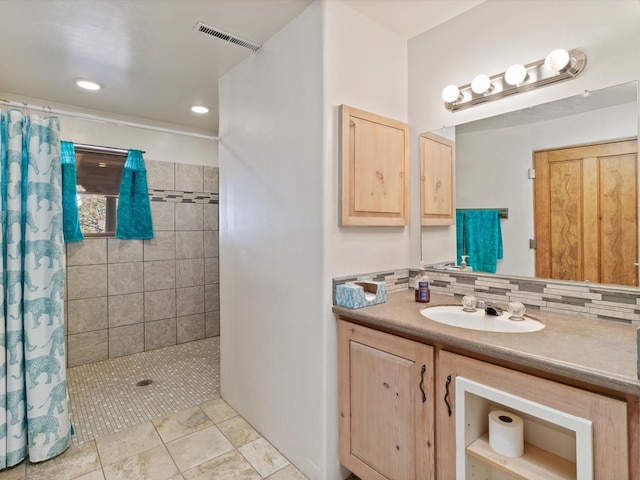 bathroom featuring tasteful backsplash, visible vents, tiled shower, and vanity