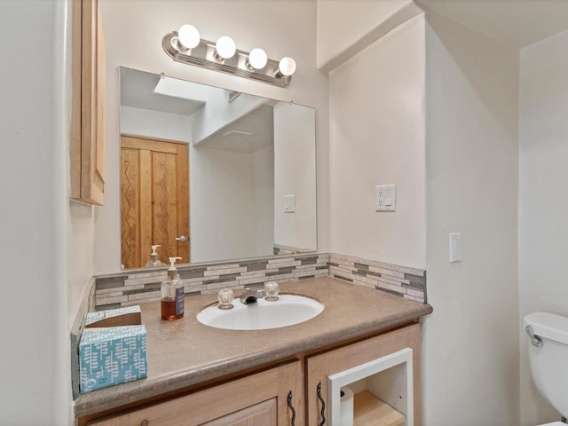 half bathroom with backsplash, vanity, and toilet