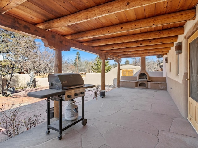 view of patio with a fireplace, fence, and grilling area