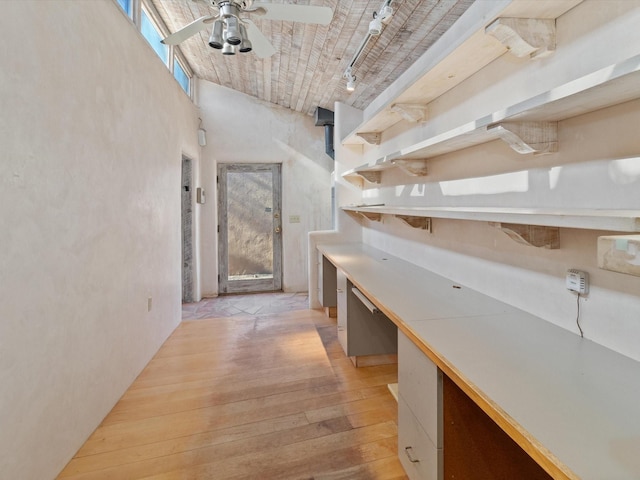 hall featuring a towering ceiling, rail lighting, and light wood finished floors