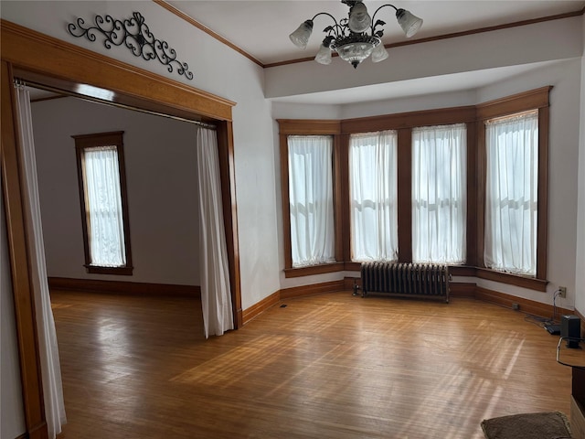 interior space with an inviting chandelier, a wealth of natural light, hardwood / wood-style flooring, and radiator heating unit