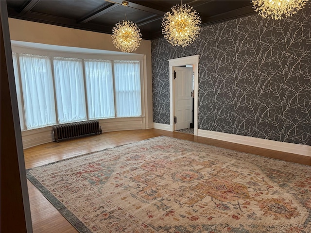 spare room with radiator, coffered ceiling, hardwood / wood-style flooring, and a notable chandelier