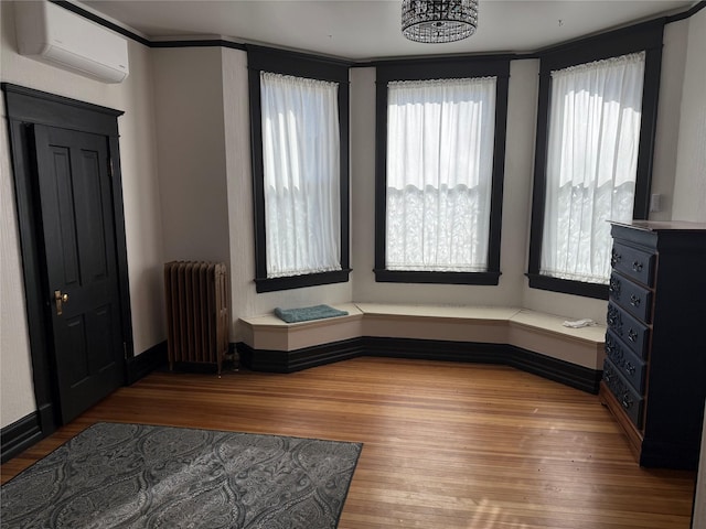 foyer with radiator, an inviting chandelier, a wall mounted AC, and hardwood / wood-style flooring