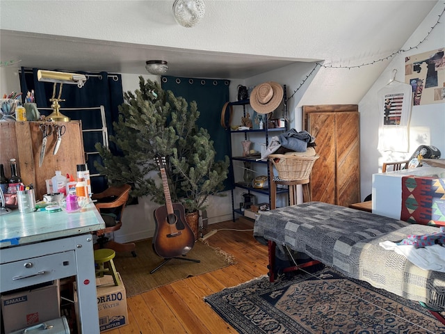 bedroom with wood-type flooring and vaulted ceiling