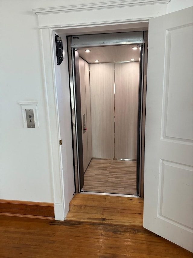 corridor featuring wood-type flooring and elevator