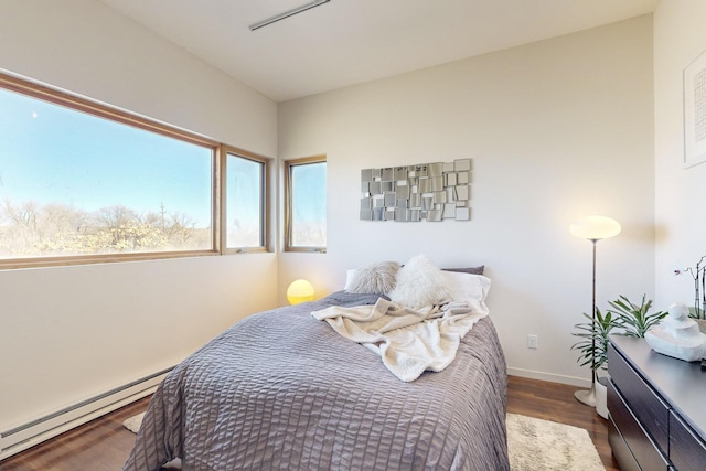 bedroom with dark wood-type flooring and a baseboard heating unit