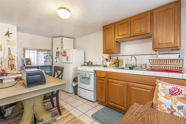 kitchen featuring tile countertops, decorative backsplash, sink, white appliances, and light tile patterned floors