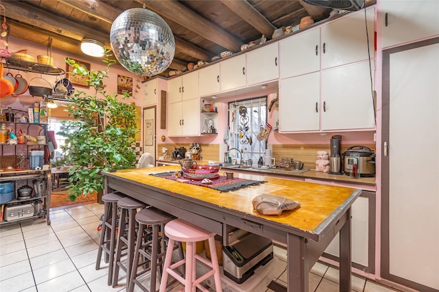 kitchen with wooden ceiling, white cabinets, beam ceiling, and a healthy amount of sunlight