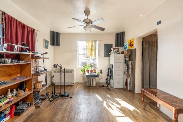 workout area with ceiling fan, hardwood / wood-style floors, and radiator heating unit