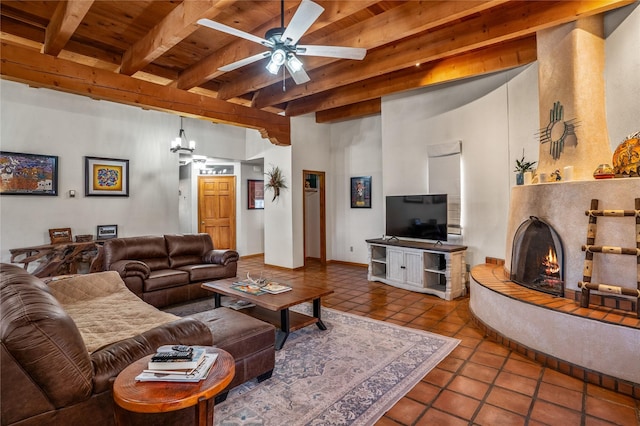 living room with tile patterned floors, beamed ceiling, a tiled fireplace, wood ceiling, and ceiling fan with notable chandelier