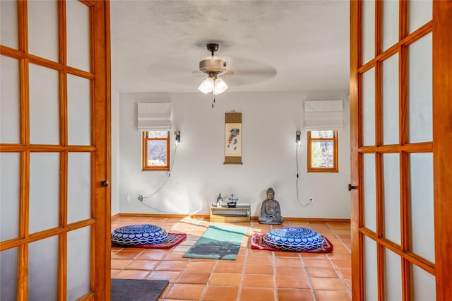 interior space featuring a textured ceiling, ceiling fan, and light tile patterned flooring