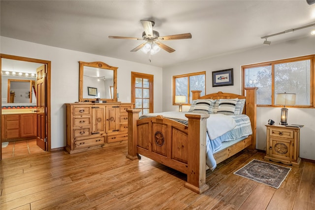 bedroom featuring ceiling fan, light hardwood / wood-style floors, and ensuite bath