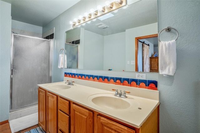 bathroom with a shower with shower door, vanity, and decorative backsplash