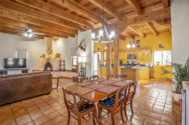 dining area featuring beam ceiling, a large fireplace, light tile patterned flooring, and wooden ceiling