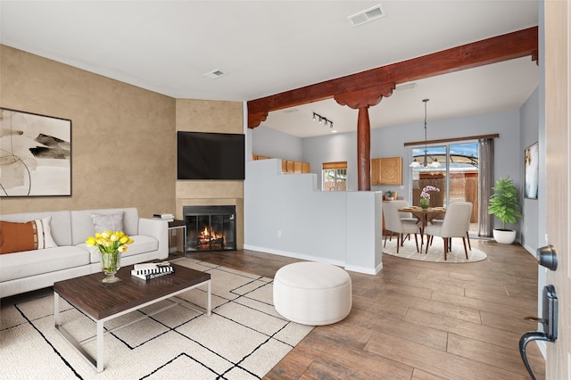 living room with light hardwood / wood-style floors and beamed ceiling