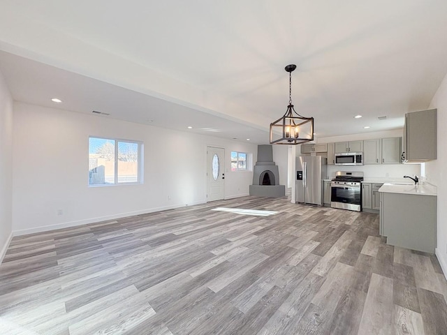 unfurnished living room featuring sink, a wealth of natural light, and light wood-type flooring