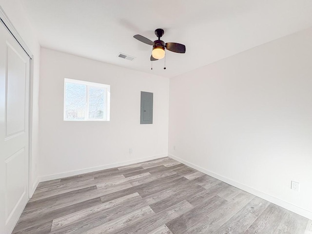 unfurnished room with electric panel, light wood-type flooring, and ceiling fan