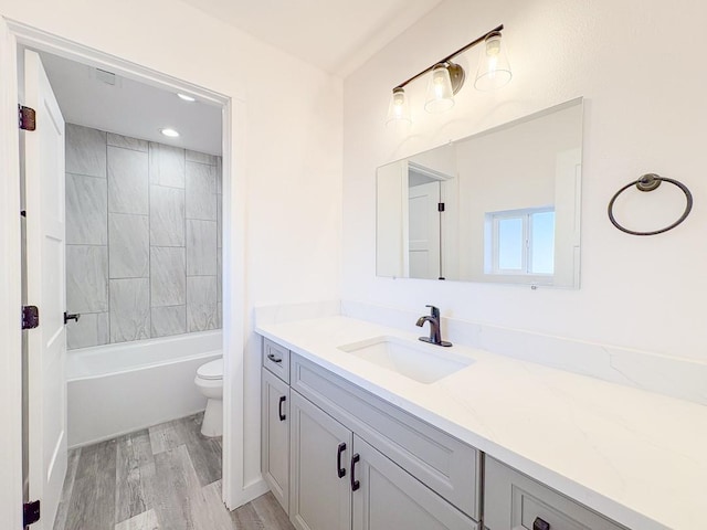 full bathroom featuring vanity, toilet, tiled shower / bath combo, and wood-type flooring