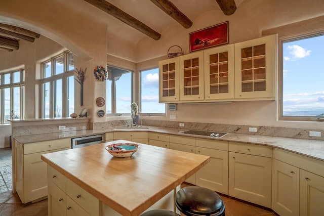 kitchen featuring beamed ceiling, dishwasher, sink, a kitchen island, and brick ceiling