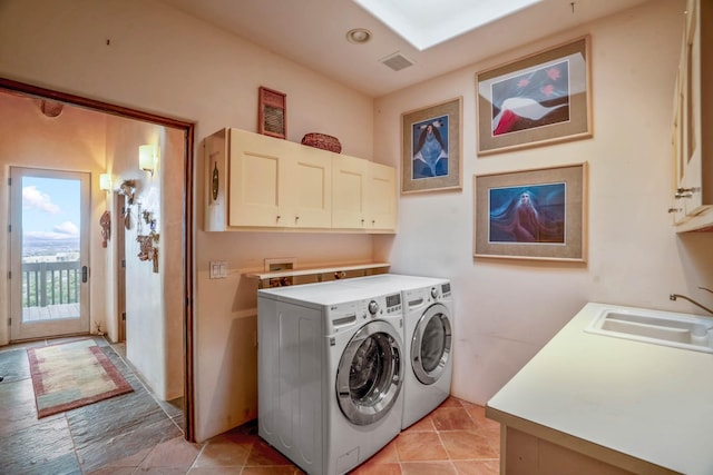 laundry room with sink, washing machine and dryer, light tile patterned floors, and cabinets