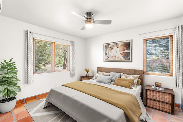 tiled bedroom with ceiling fan and multiple windows