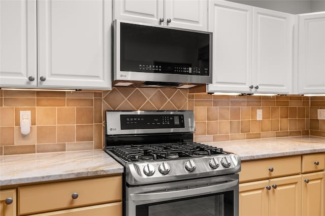 kitchen featuring light stone countertops, white cabinetry, backsplash, and stainless steel appliances