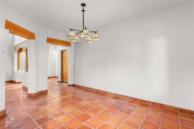 tiled empty room featuring a chandelier