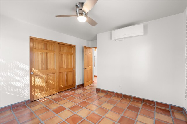 spare room with an AC wall unit, ceiling fan, and tile patterned floors