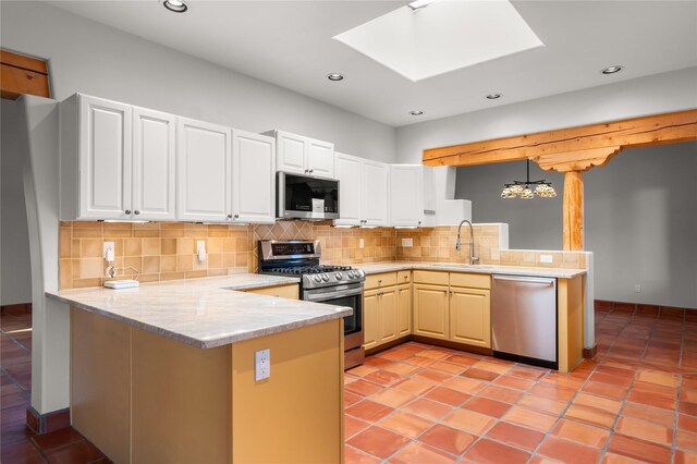 kitchen with hanging light fixtures, kitchen peninsula, stainless steel appliances, and tasteful backsplash