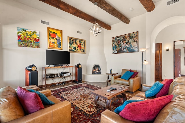 living room featuring beamed ceiling, a notable chandelier, and a large fireplace