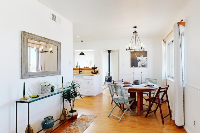 dining space with a notable chandelier, light hardwood / wood-style floors, and sink