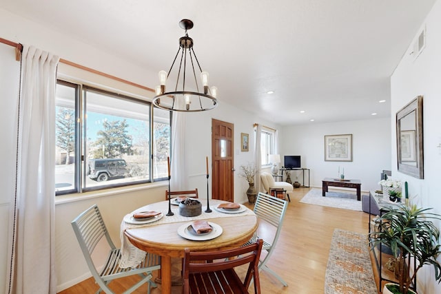 dining room with light hardwood / wood-style floors, a wealth of natural light, and an inviting chandelier