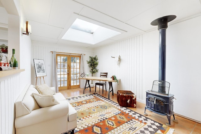 tiled living room featuring a wood stove, wood walls, and french doors