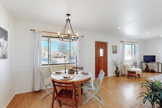 dining space with light hardwood / wood-style floors and a chandelier