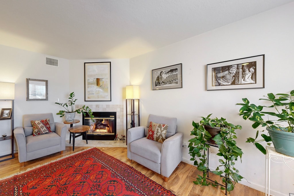 living area with a tiled fireplace and light hardwood / wood-style floors