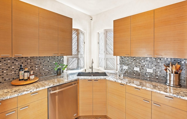 kitchen with light stone countertops, sink, stainless steel dishwasher, and decorative backsplash