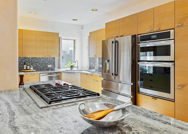 kitchen featuring light stone counters, sink, tasteful backsplash, and appliances with stainless steel finishes