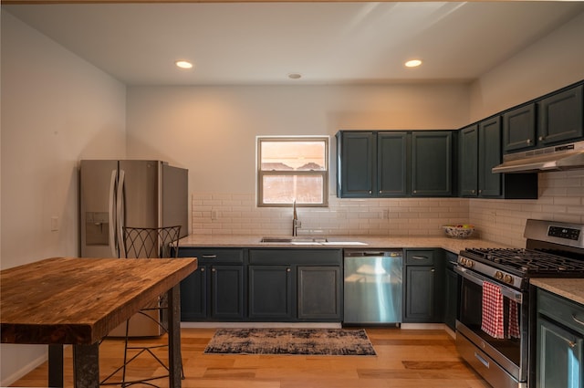 kitchen with sink, tasteful backsplash, light stone countertops, light hardwood / wood-style floors, and stainless steel appliances