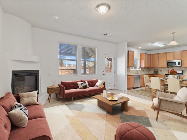 tiled living room with sink, a large fireplace, and a textured ceiling