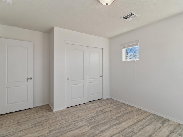 3110 Floras Del Sol, Santa Fe, NM 87507 - unfurnished bedroom with a textured ceiling, light hardwood / wood-style flooring, and a closet