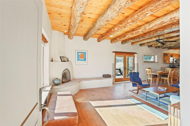 living room with ceiling fan, a fireplace, wooden ceiling, french doors, and beamed ceiling