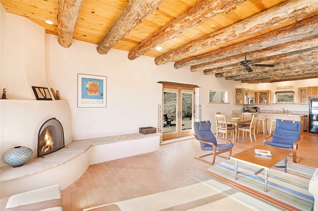 living room featuring beam ceiling, wooden ceiling, and ceiling fan