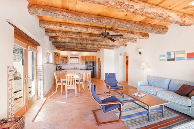 living room with beam ceiling, a wealth of natural light, and ceiling fan