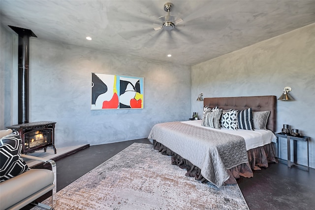 bedroom featuring ceiling fan, concrete floors, and a wood stove