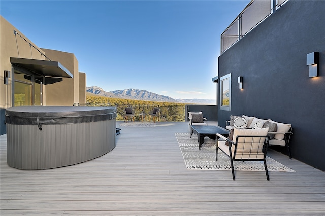 deck with an outdoor hangout area, a hot tub, and a mountain view