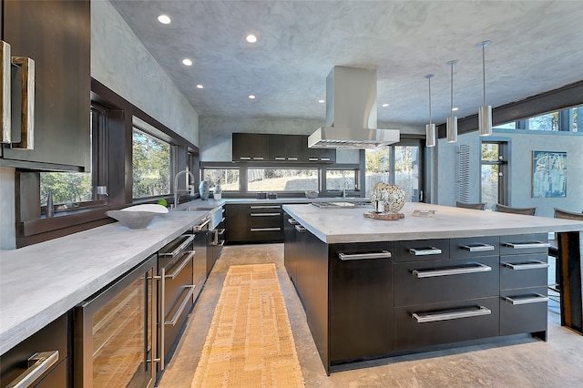 kitchen with sink, island range hood, hanging light fixtures, a kitchen island, and beverage cooler