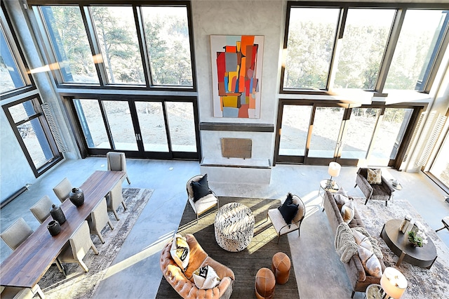 living room featuring a towering ceiling, concrete flooring, and a healthy amount of sunlight