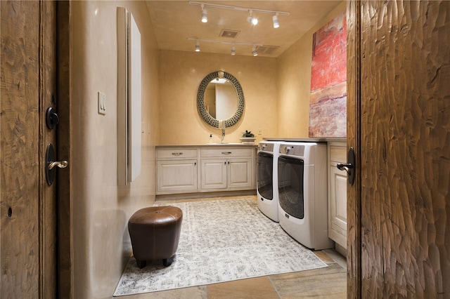 clothes washing area featuring cabinets, washer and dryer, and sink