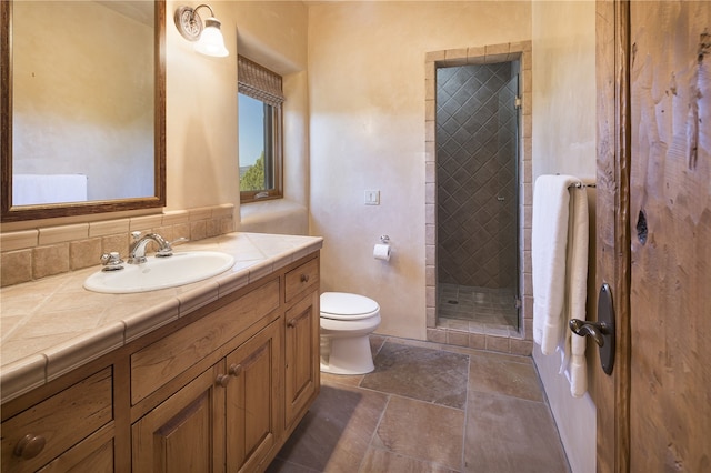 bathroom with vanity, a tile shower, and toilet