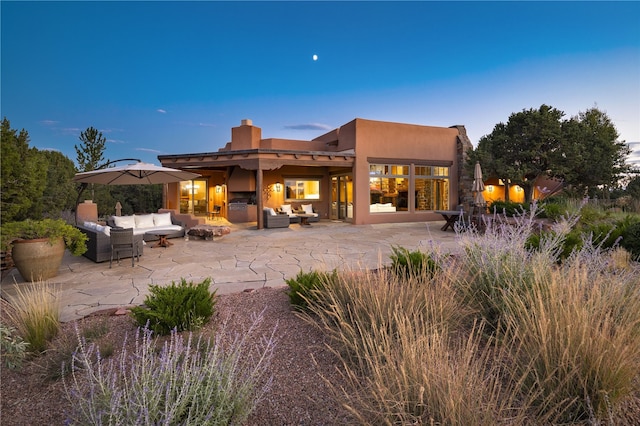 back house at dusk with outdoor lounge area and a patio